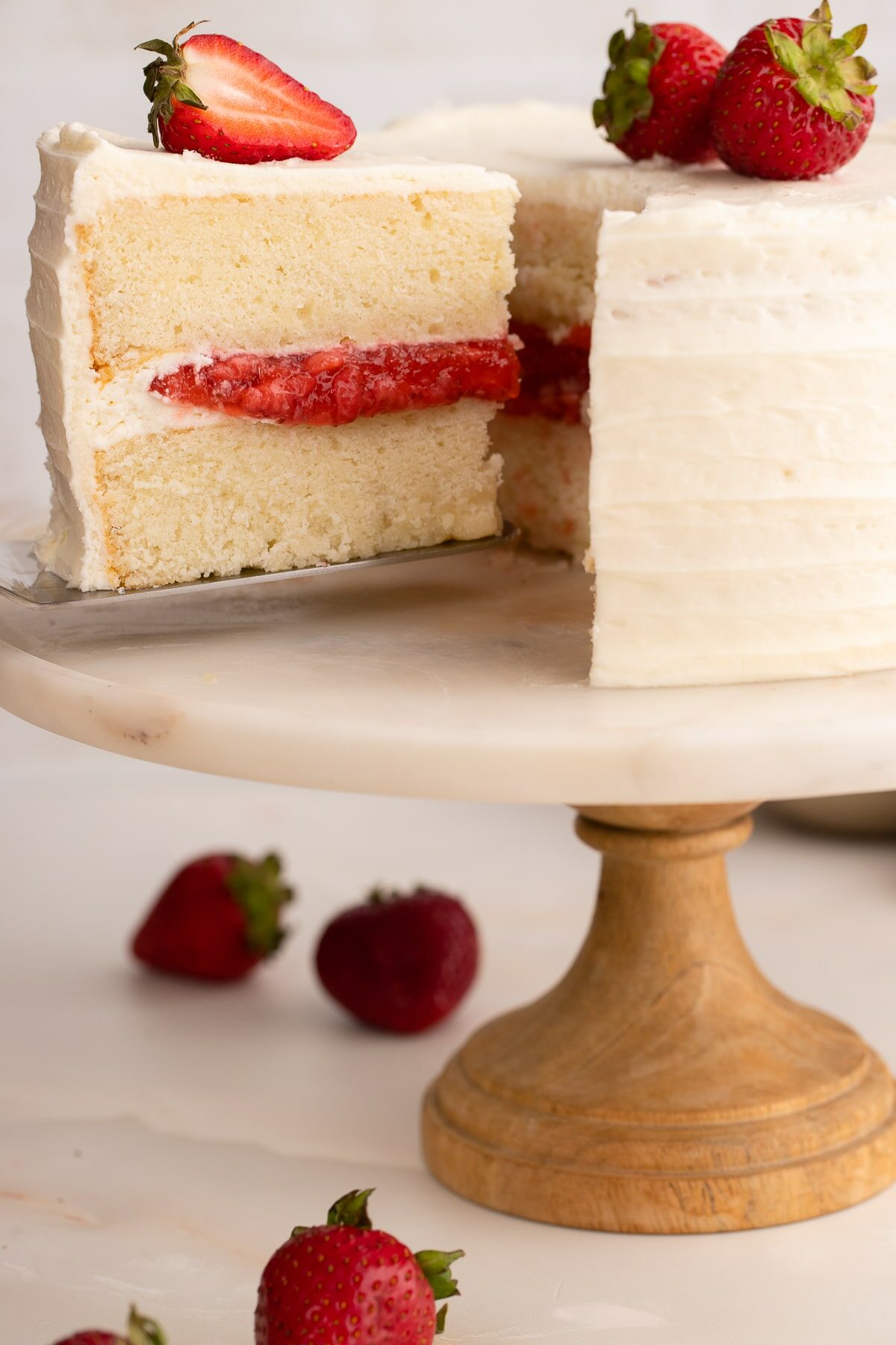 slicing a Vanilla Cake with Strawberry Filling.