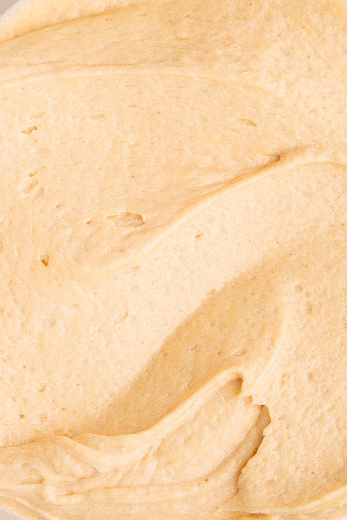 peanut butter cream cheese frosting swirled in bowl up close.