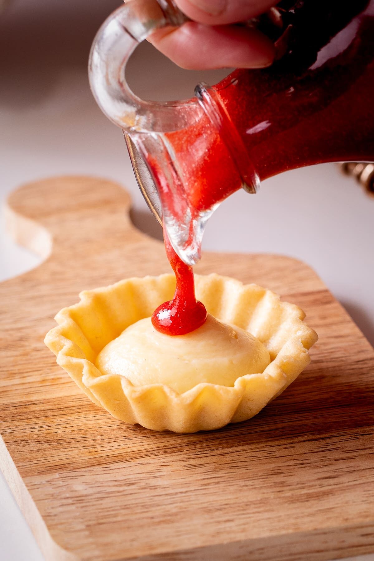 pouring strawberry coulis on tart.