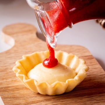 pouring strawberry coulis on tart.