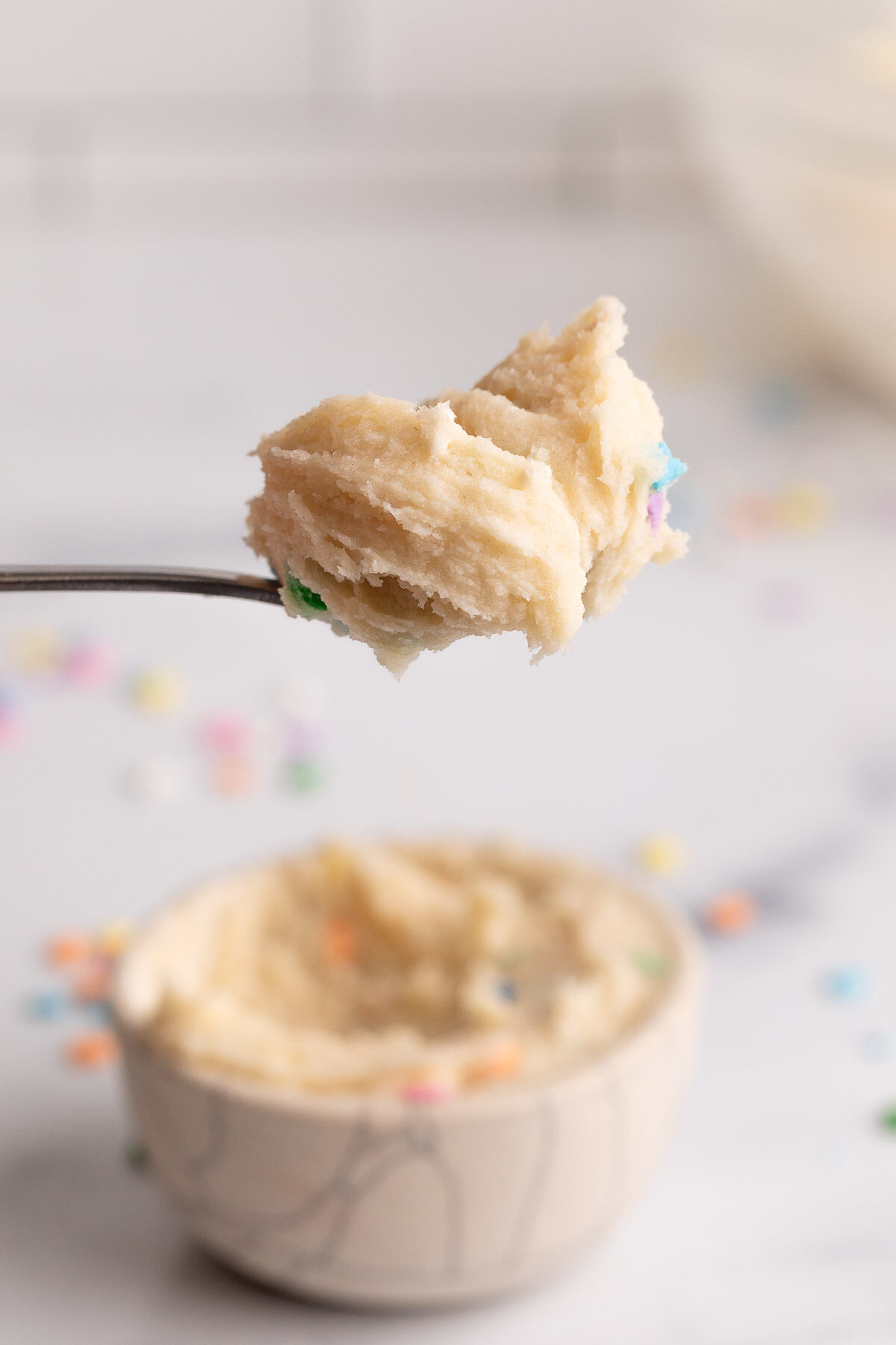 edible sugar cookie dough in bowl and on spoon.