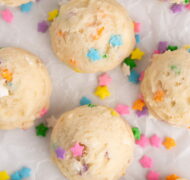 edible sugar cookie dough balls on parchment with sprinkles.