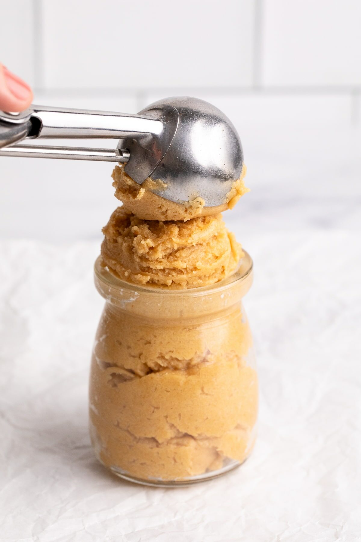 scooping peanut butter edible cookie dough in container.
