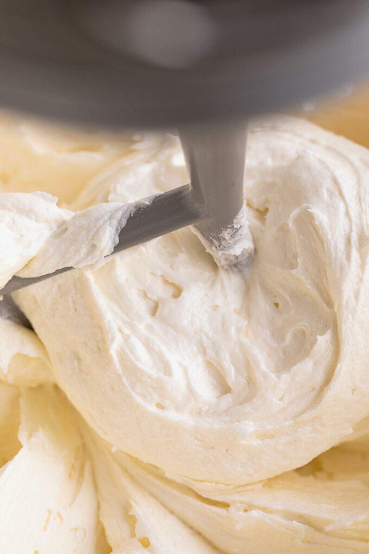 almond buttercream frostin on beater in bowl close up.