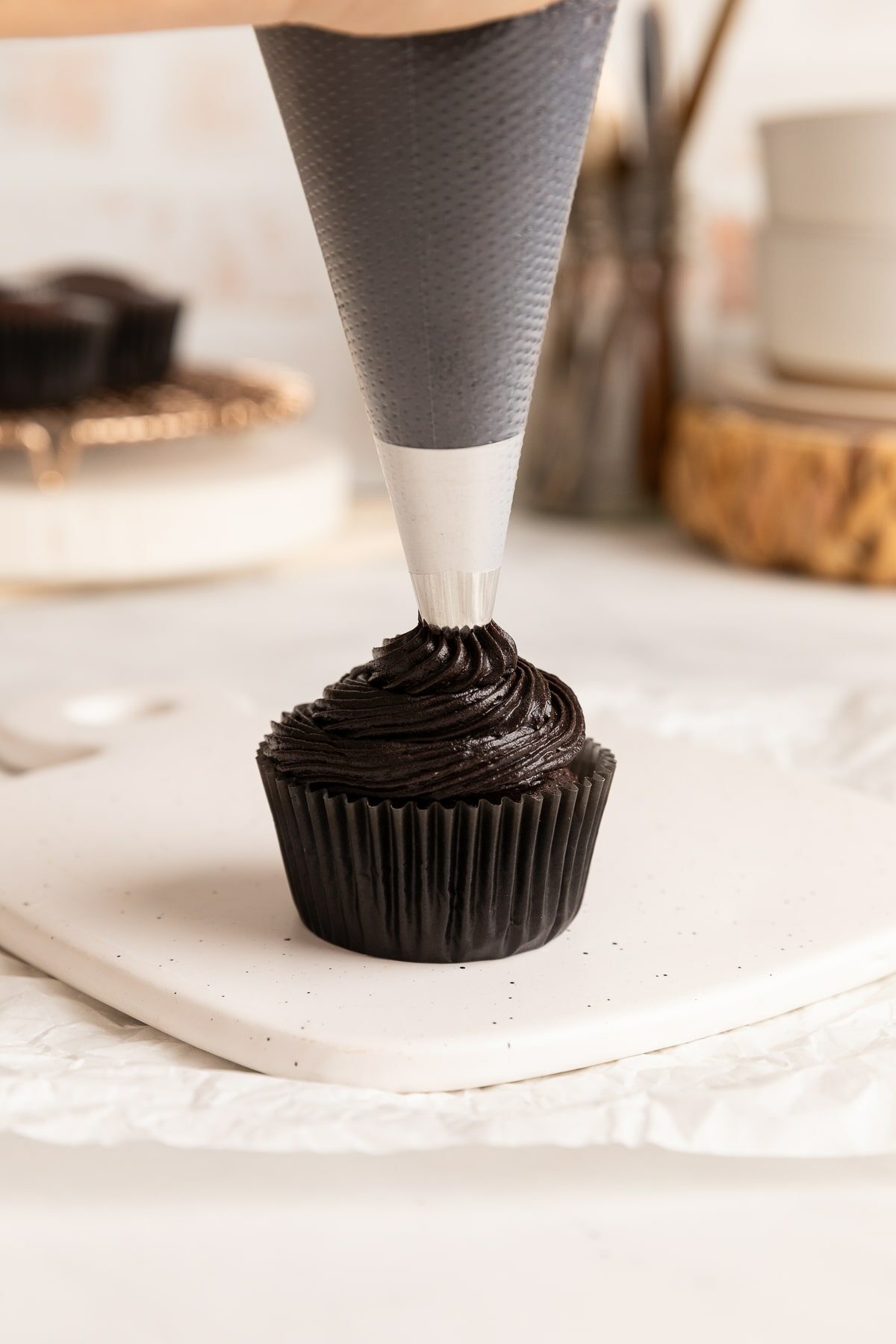 piping black frosting on cupcake.