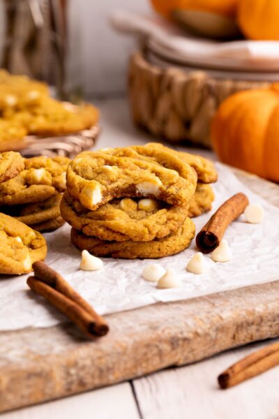 pumpkin white chocolate chip cookies stacked with bite taken out.