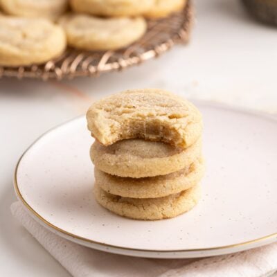 brown butter sugar cookies stacked on a plate with a bit taken out..
