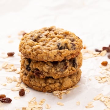 three stacked oatmeal raisin cookies on parchment.