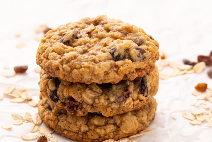 three stacked oatmeal raisin cookies on parchment.