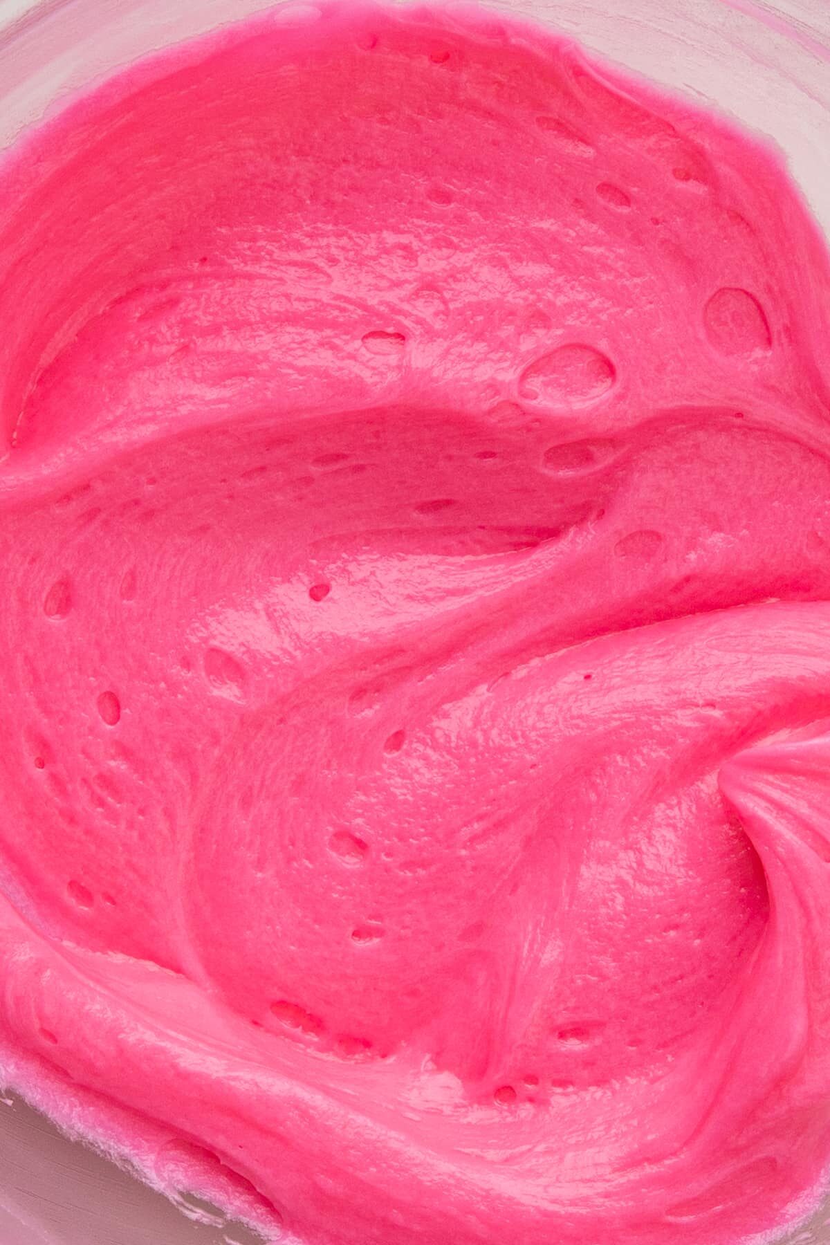 vibrant pink frosting in bowl up close.