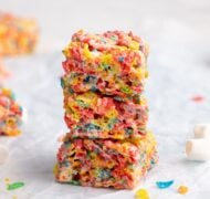 fruity pebbles treats stacked on parchment.