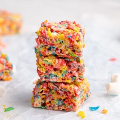 fruity pebbles treats stacked on parchment.