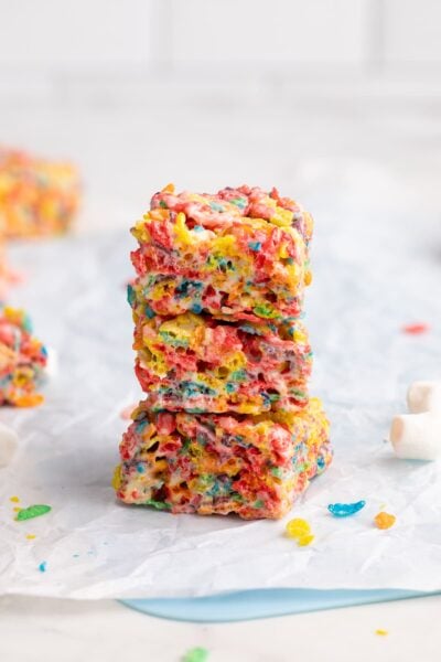 fruity pebbles treats stacked on parchment.