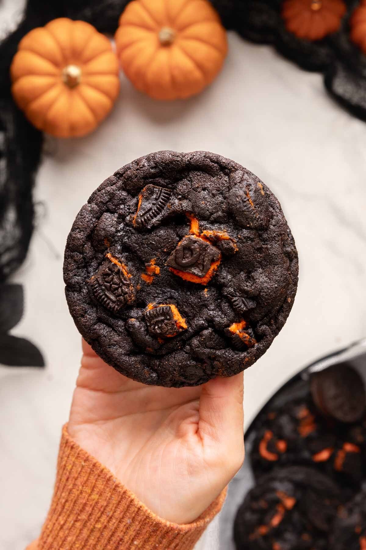 holding oreo halloween chocolate cookie.