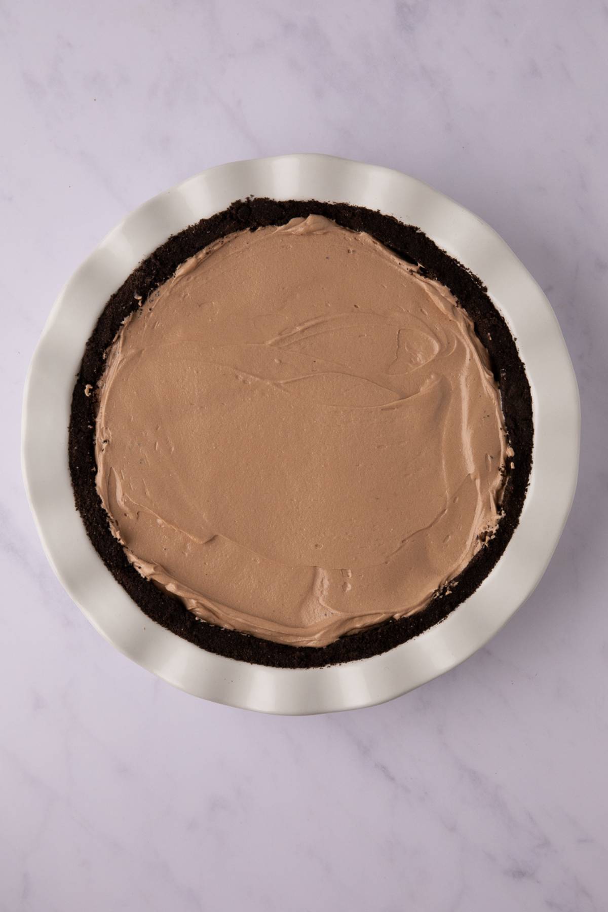 no bake nutella pie in a white pie tin on a grey counter.