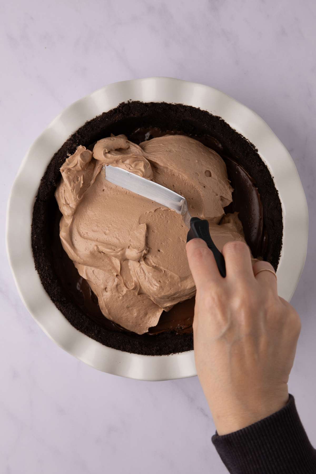 smoothing nutella pie filling in the pie crust with an offset sptaula.