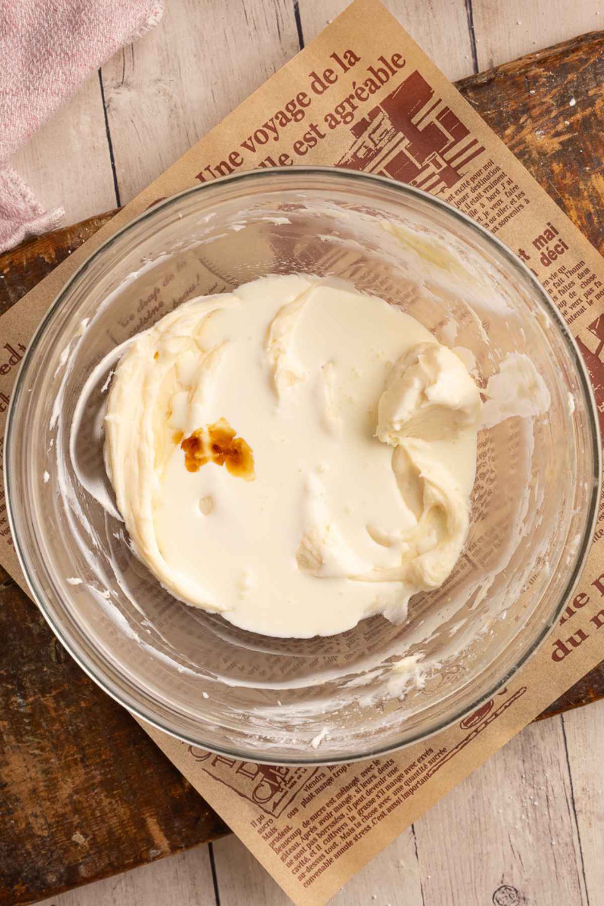 bowl of vanilla cheesecake filling in a glass bowl with heavy whipping cream and vanilla added.