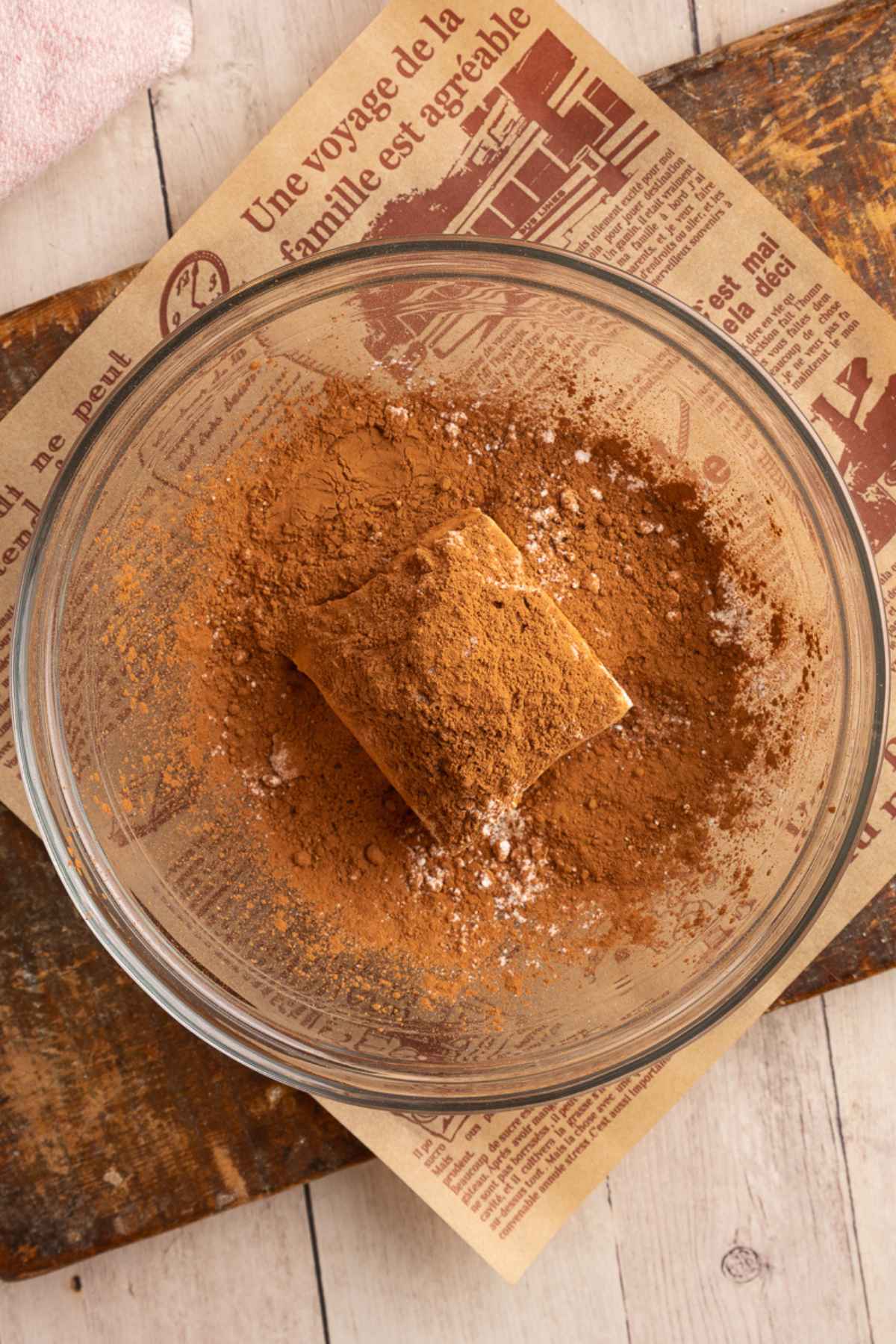 glass bowl with cream cheese, powdered sugar, and cocoa powder unmixed.