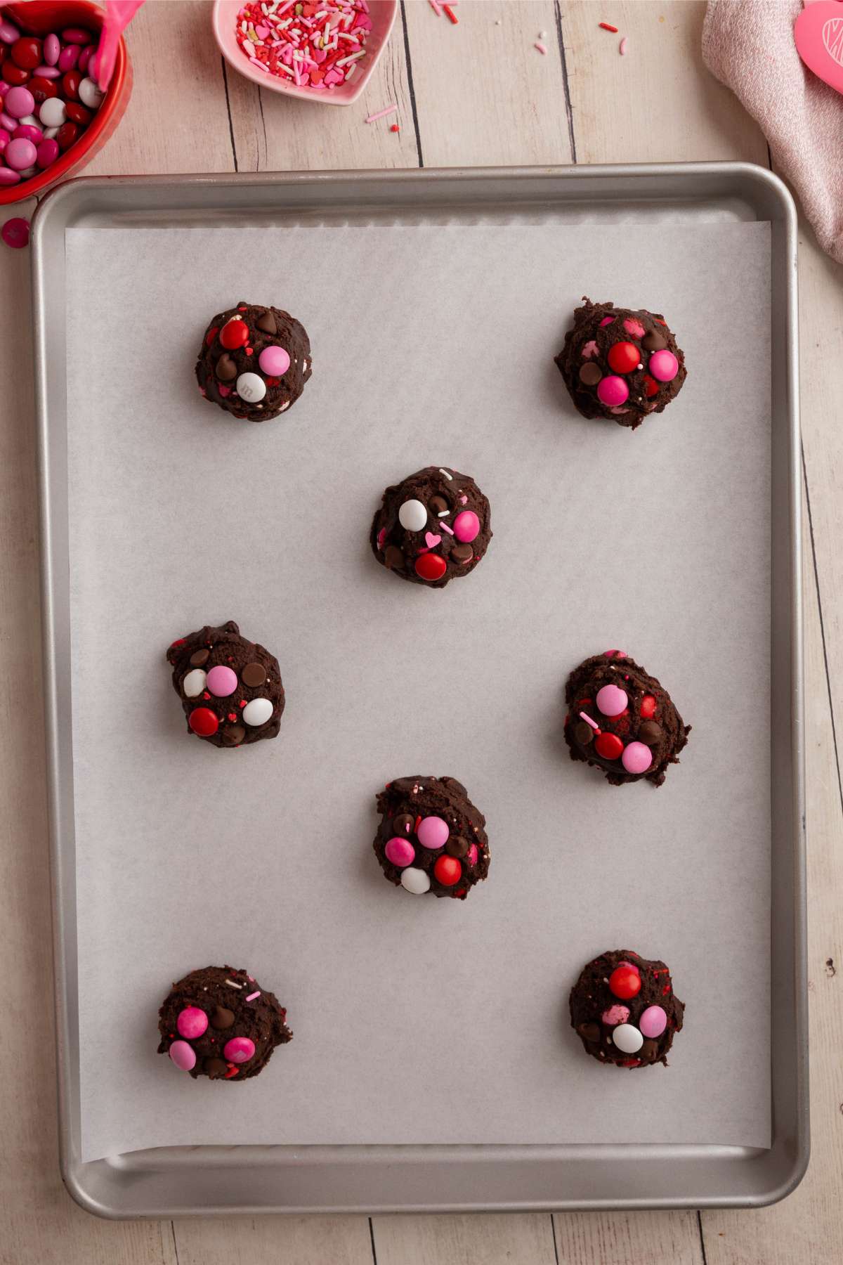 8 unbaked cookies on a parchment lined baking sheet.