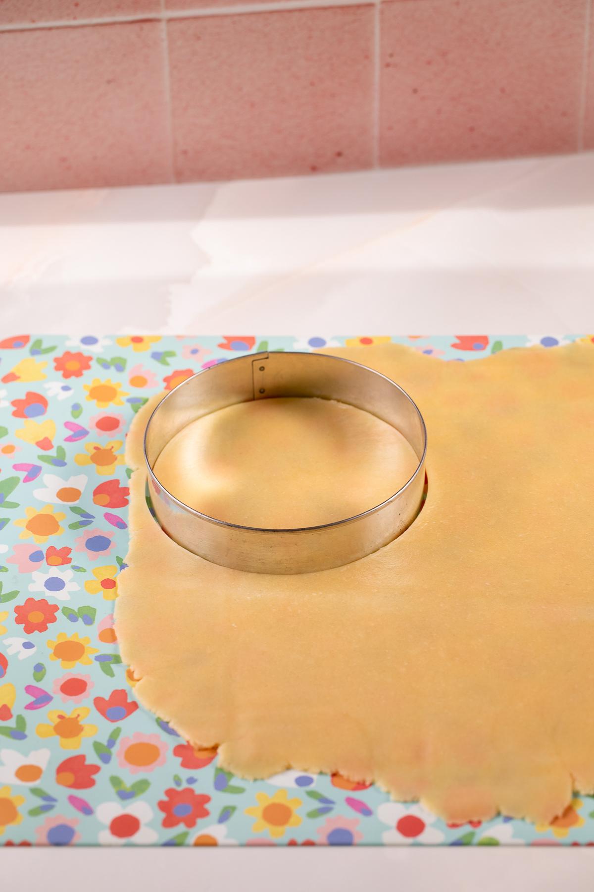 using a round cookie cutter to cut out tarlets to press into a tart pan.
