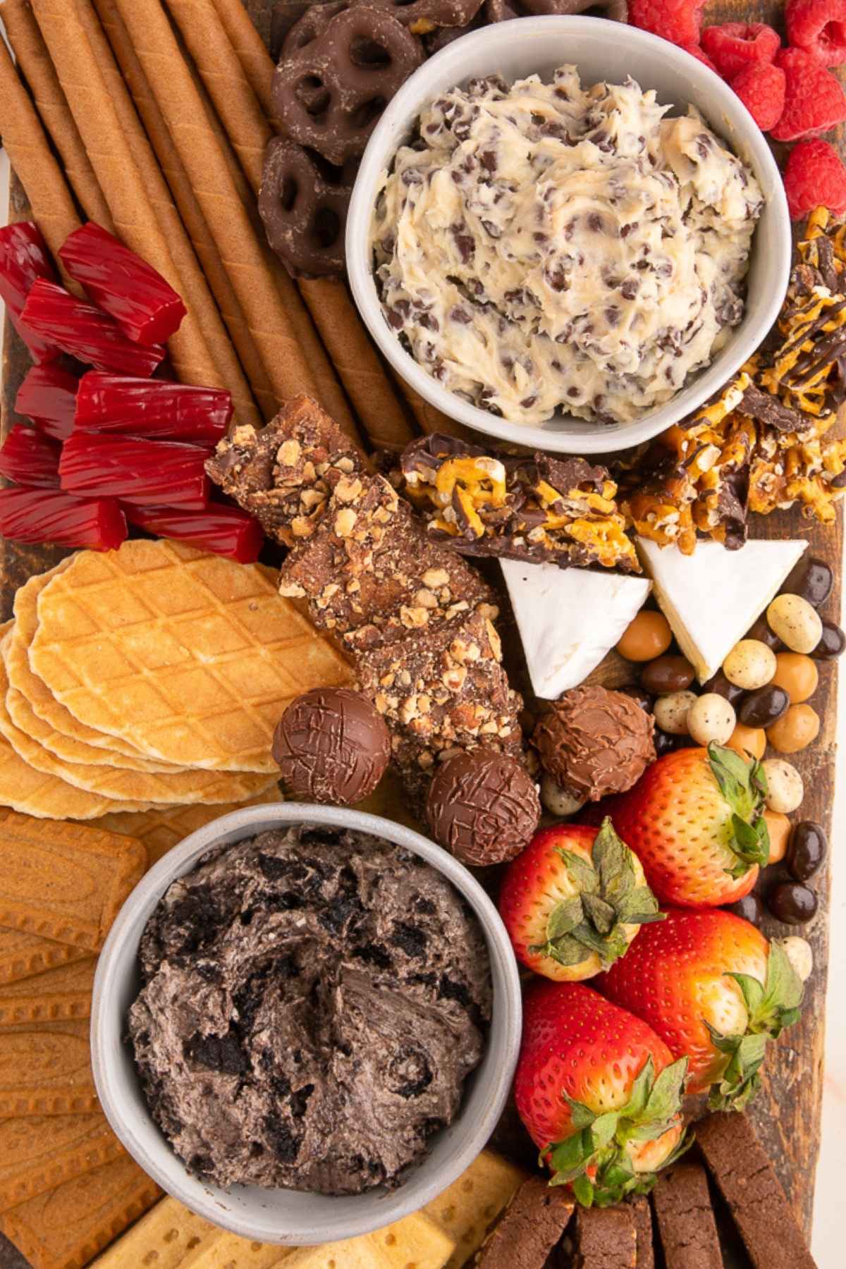 dessert charcuterie board with dessert dips, fruit, chips, truffles, and cheese up close.