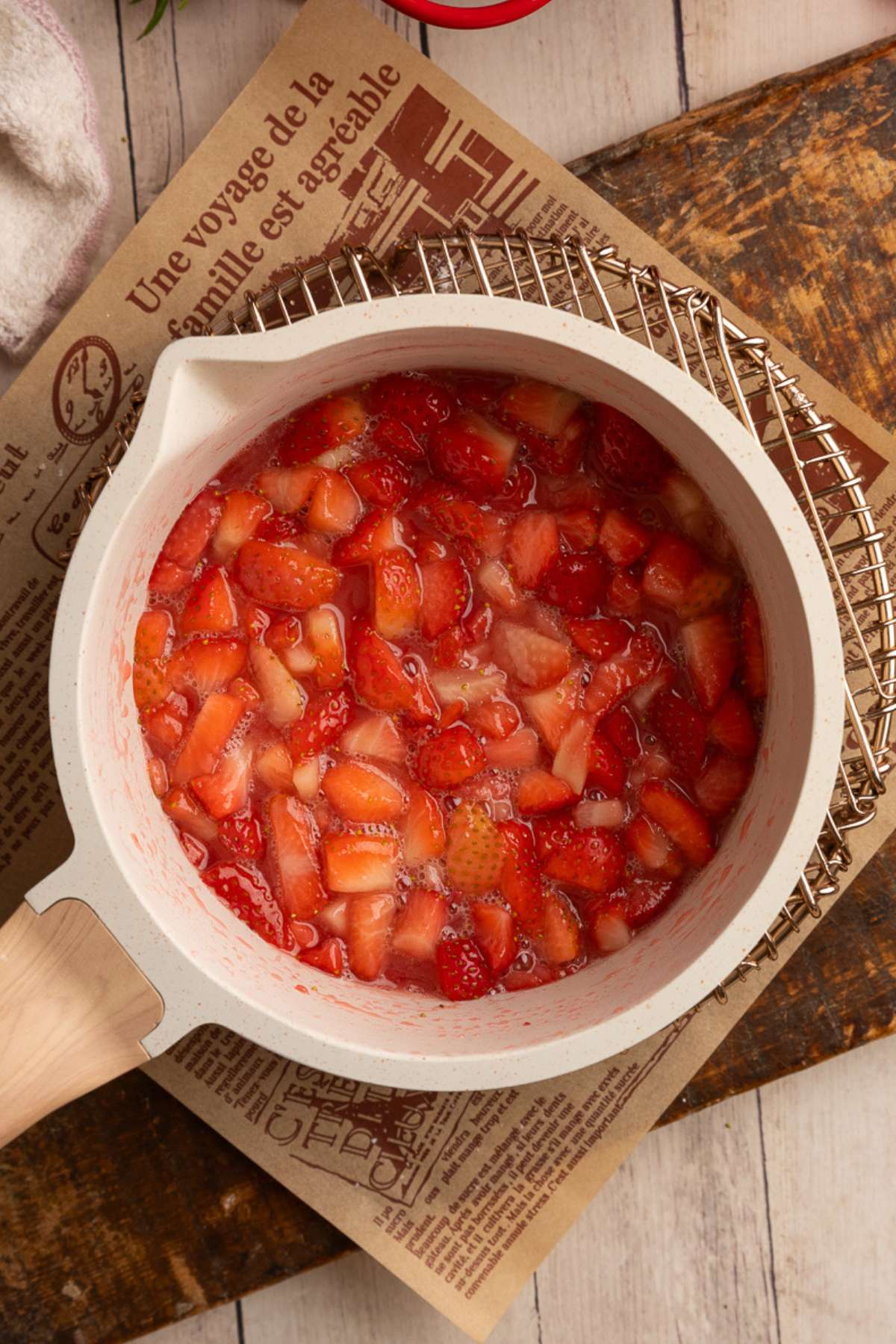 cooking strawberry hand pie filling in a cream colored saucepan.