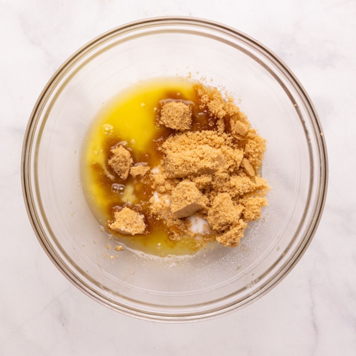 adding granulated and brown sugar to melted butter in glass bowl.
