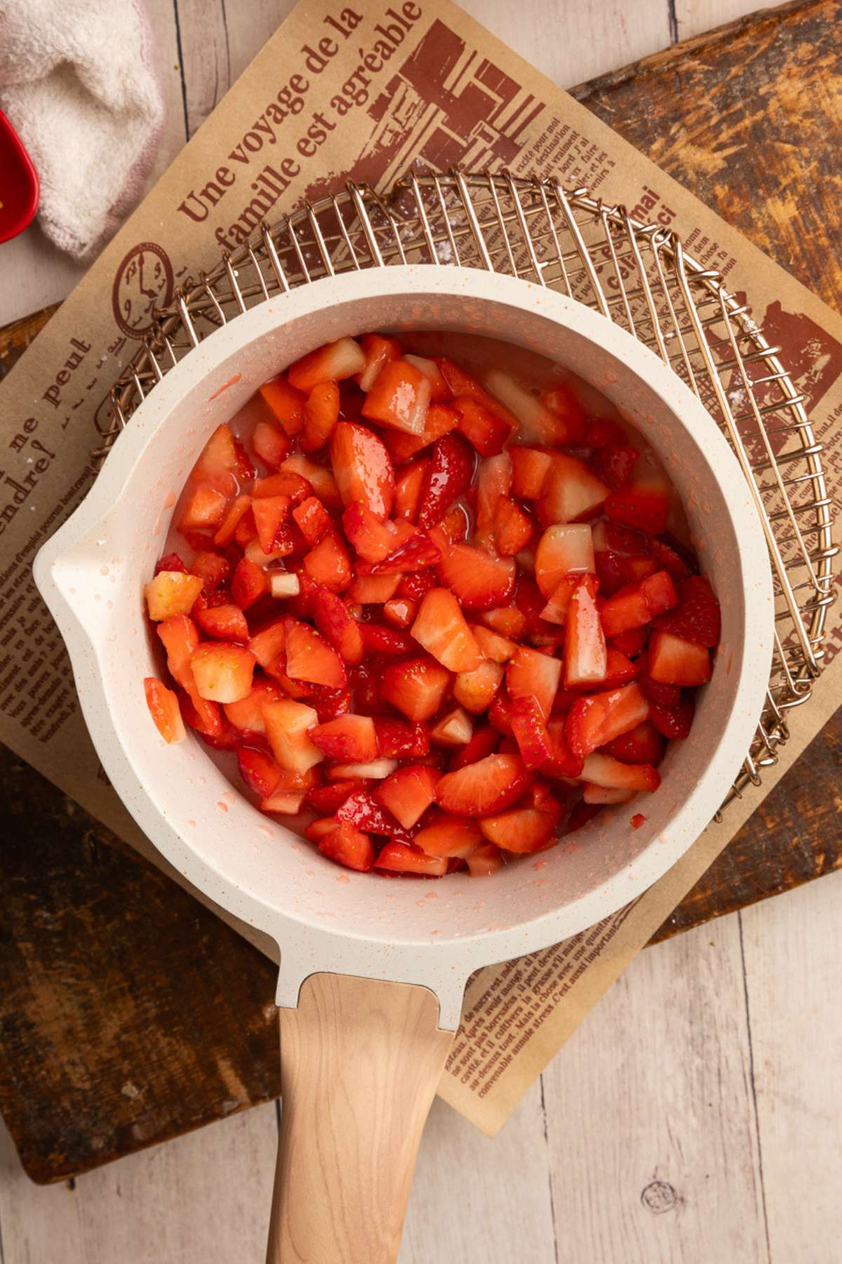 mixed up strawberry filling ingredients in a cream colored saucepan on metal rack.