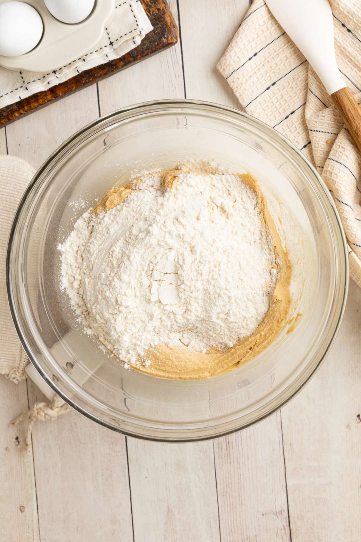 flour on top of the cookie dough, unmixed, in a glass bowl.