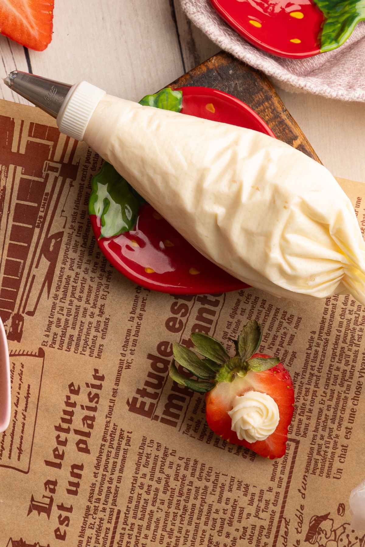 piping the vanilla cream cheese filling into a strawberry half.