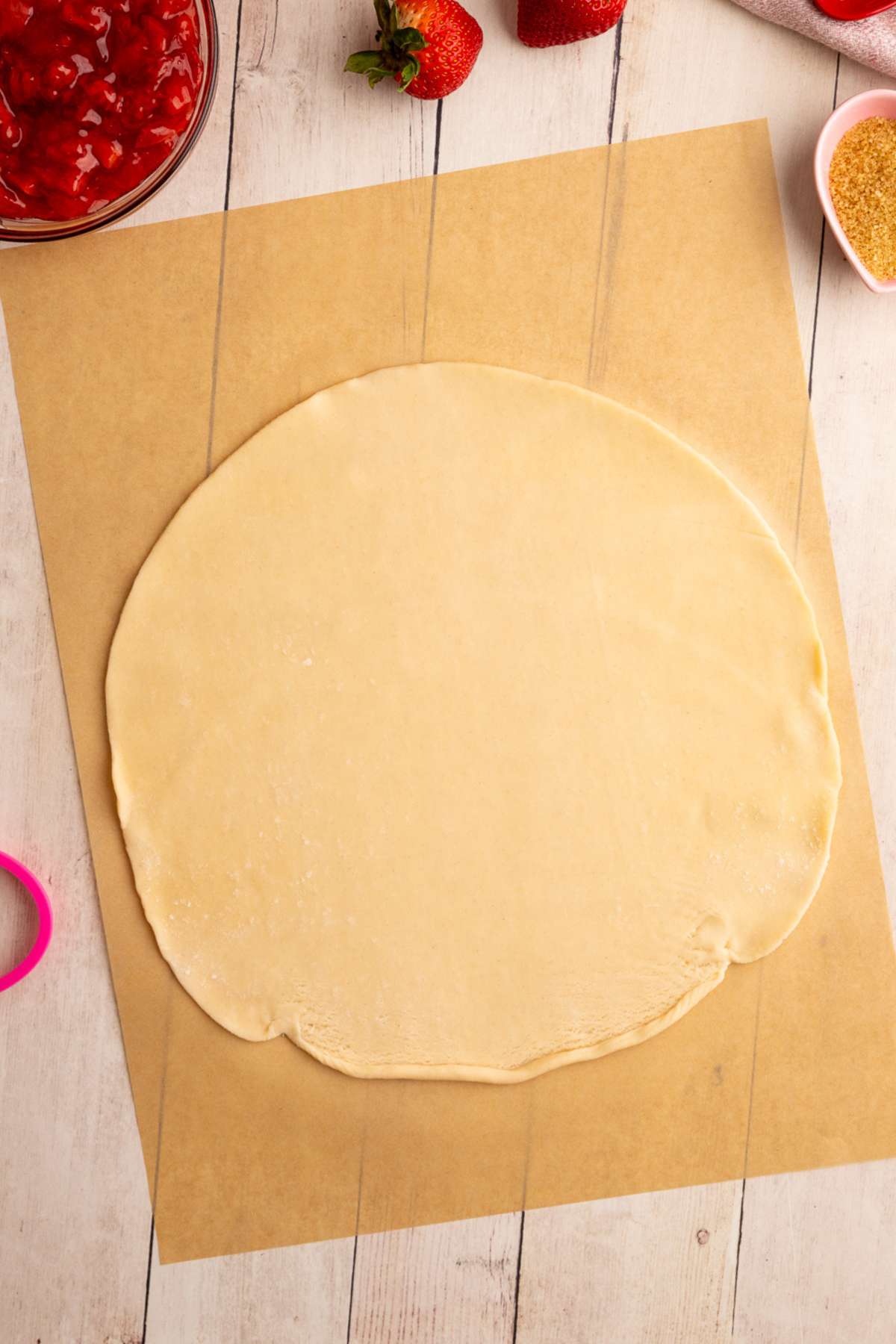 pre-made pie crust rolled out on brown parchment paper.