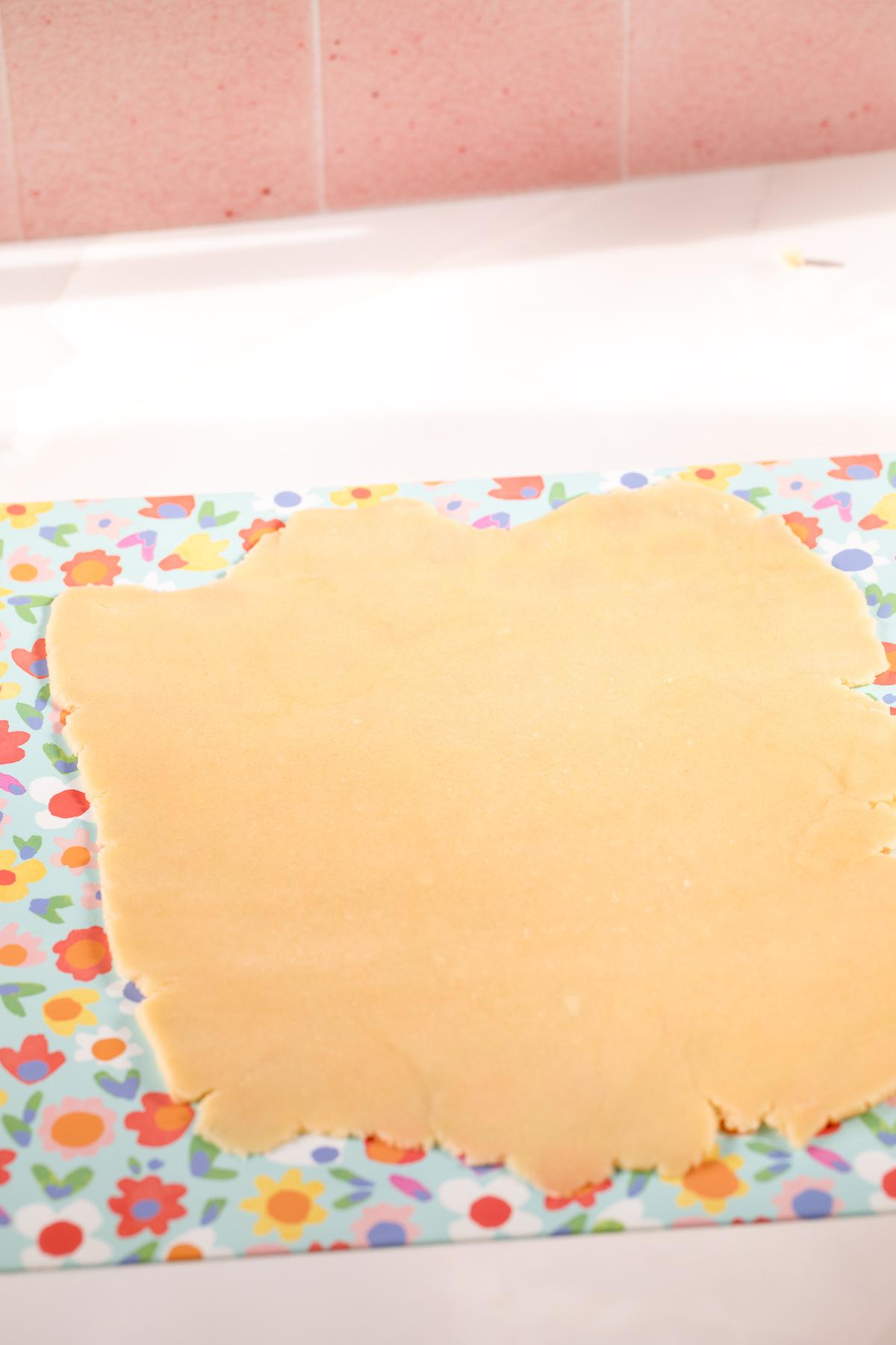 rolled out tartlet dough on a flower printed silicone mat.