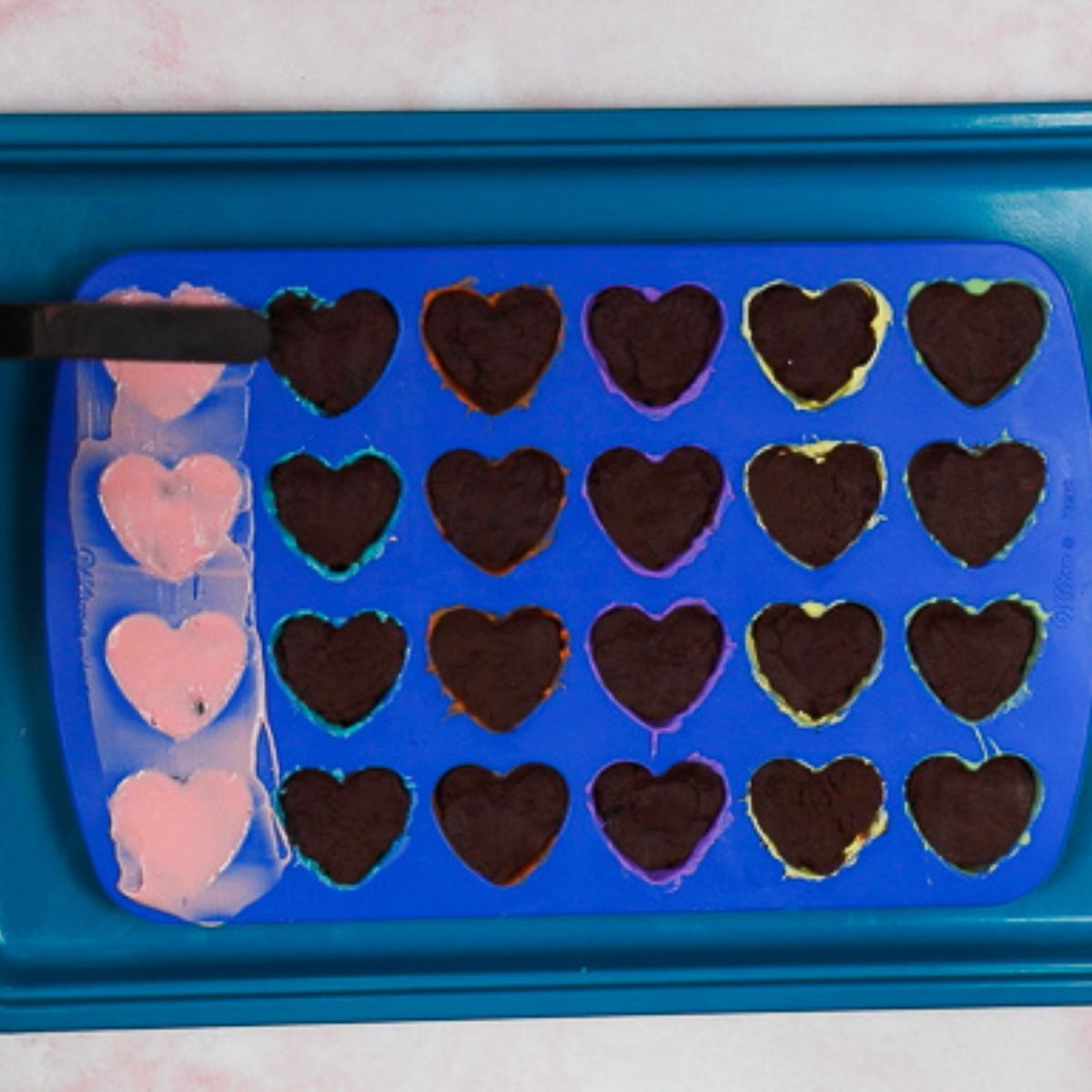 smoothing chocolate on top of cake filled silicone molds.