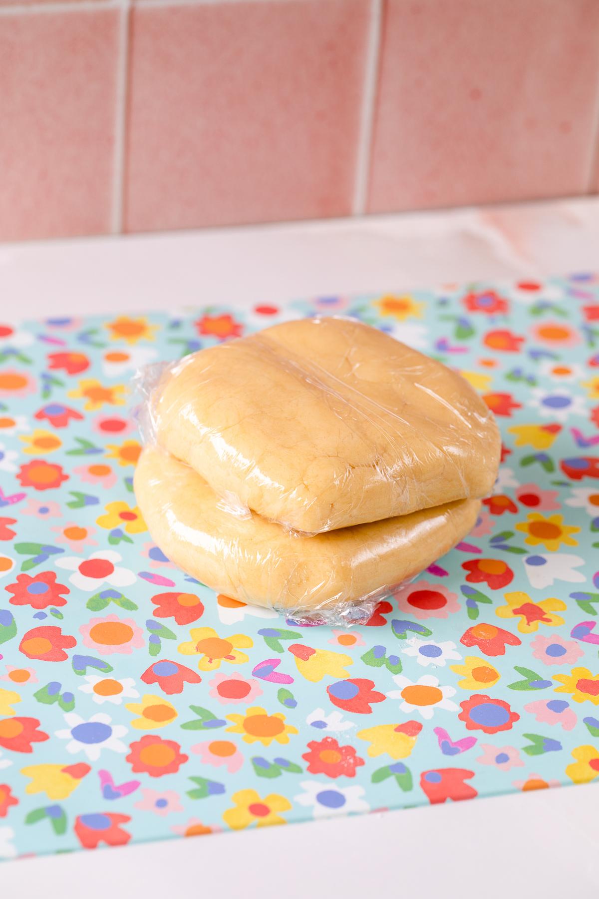 two discs of wrapped tartlet dough on silicone mat, ready for chilling.