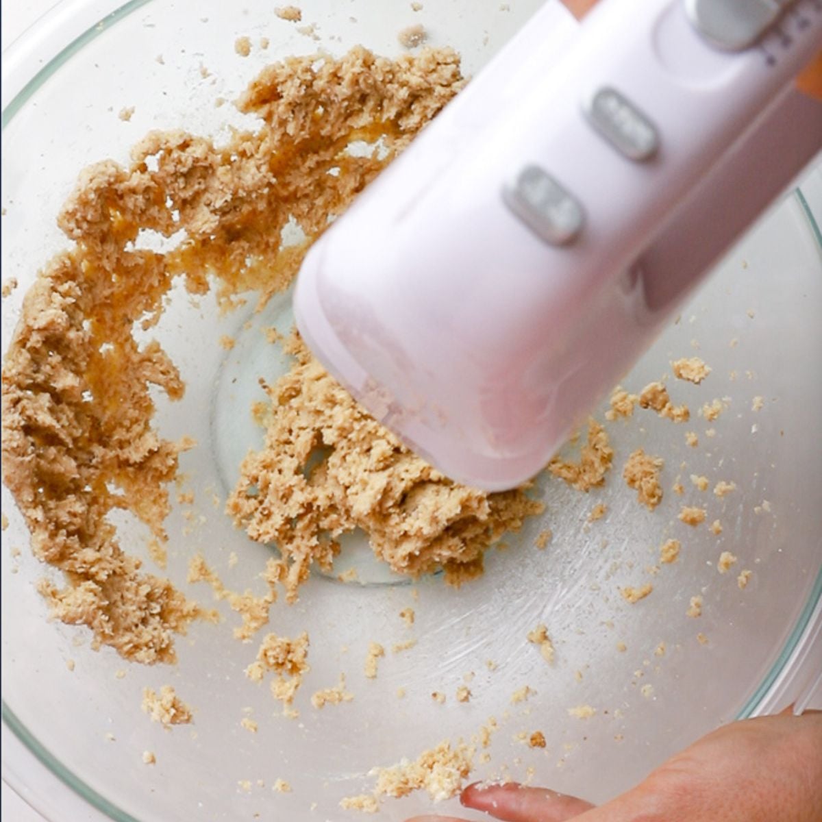 creaming butter and sugar with white hand held mixer in glass bowl.