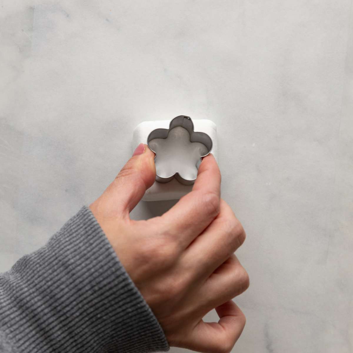 cutting out a flower from a square stackers marshmallow using a metal cookie cutter.