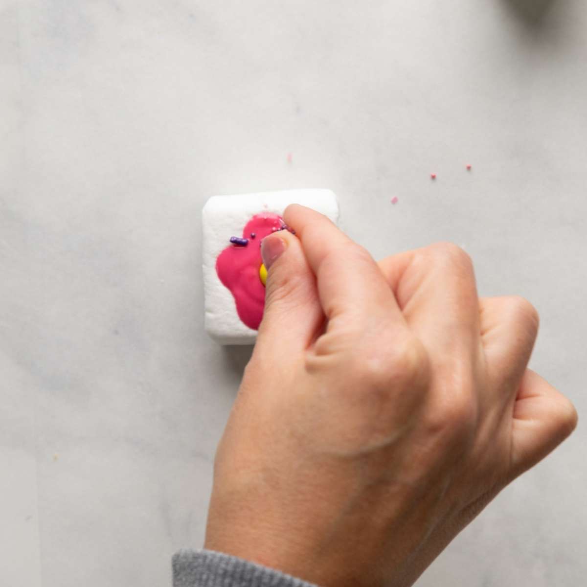 adding sprinkles to a marshmallow pop.