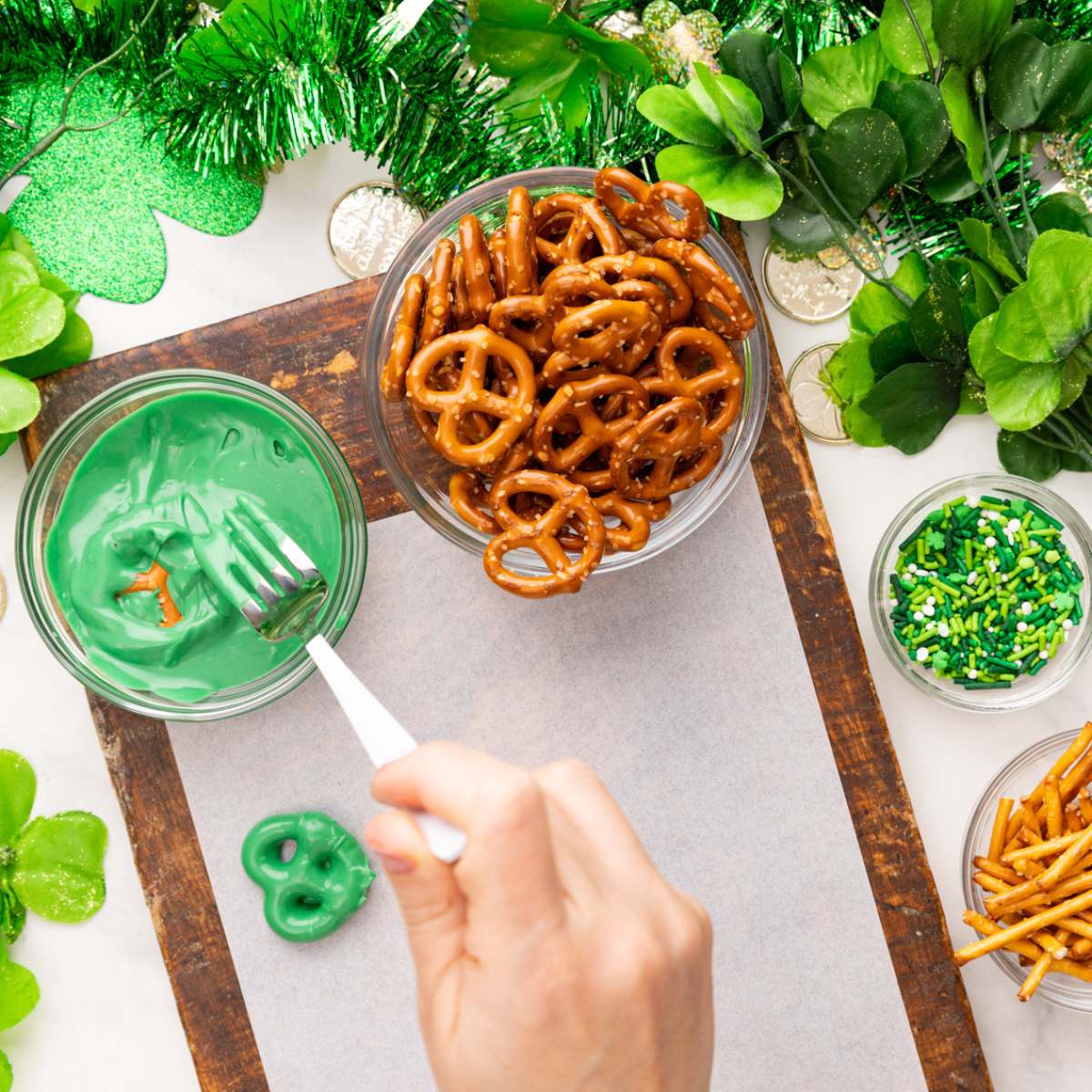 dipping a pretzel into chocolate using a fork.