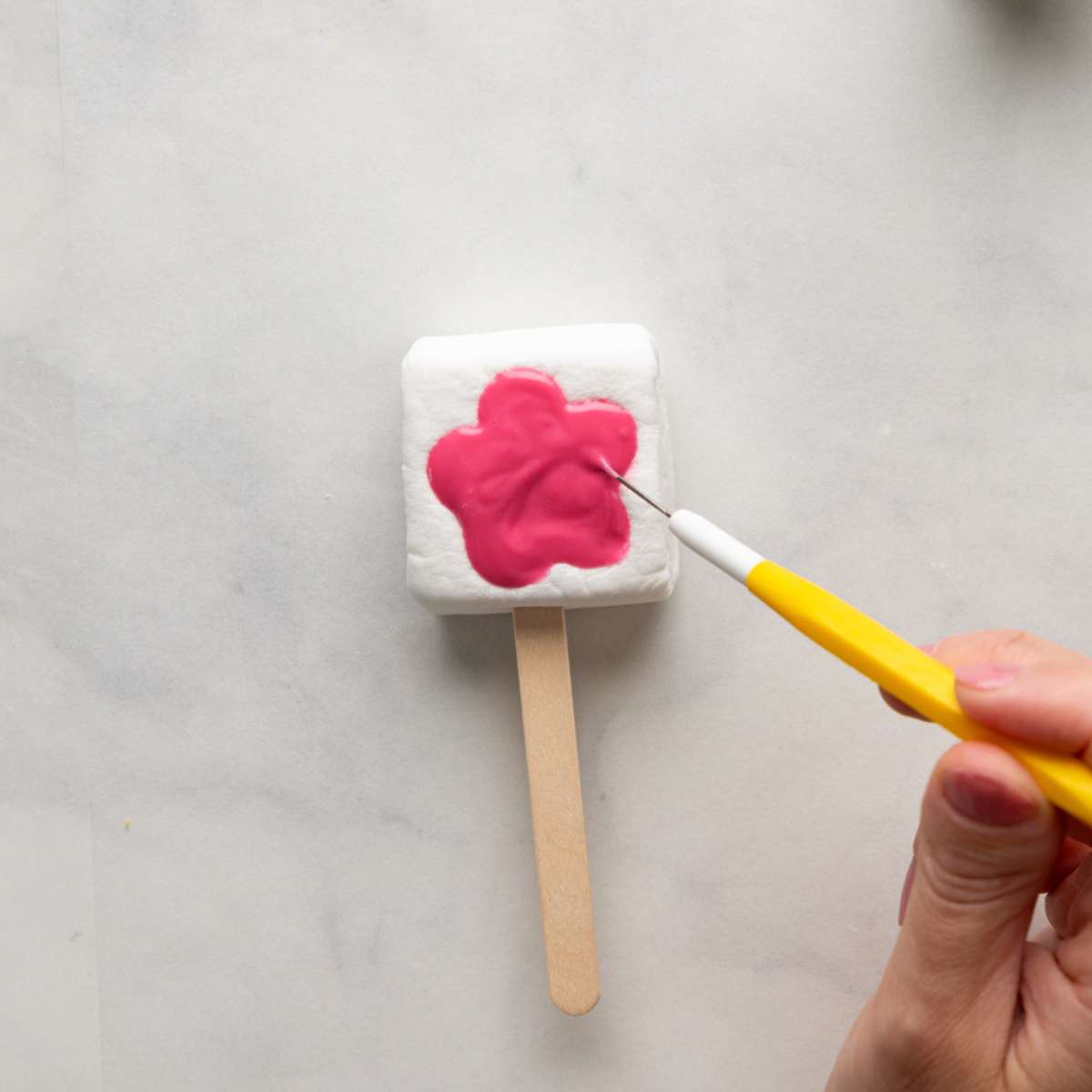 using a scribe to ensure the chocolate is even in the marshmallow pop.