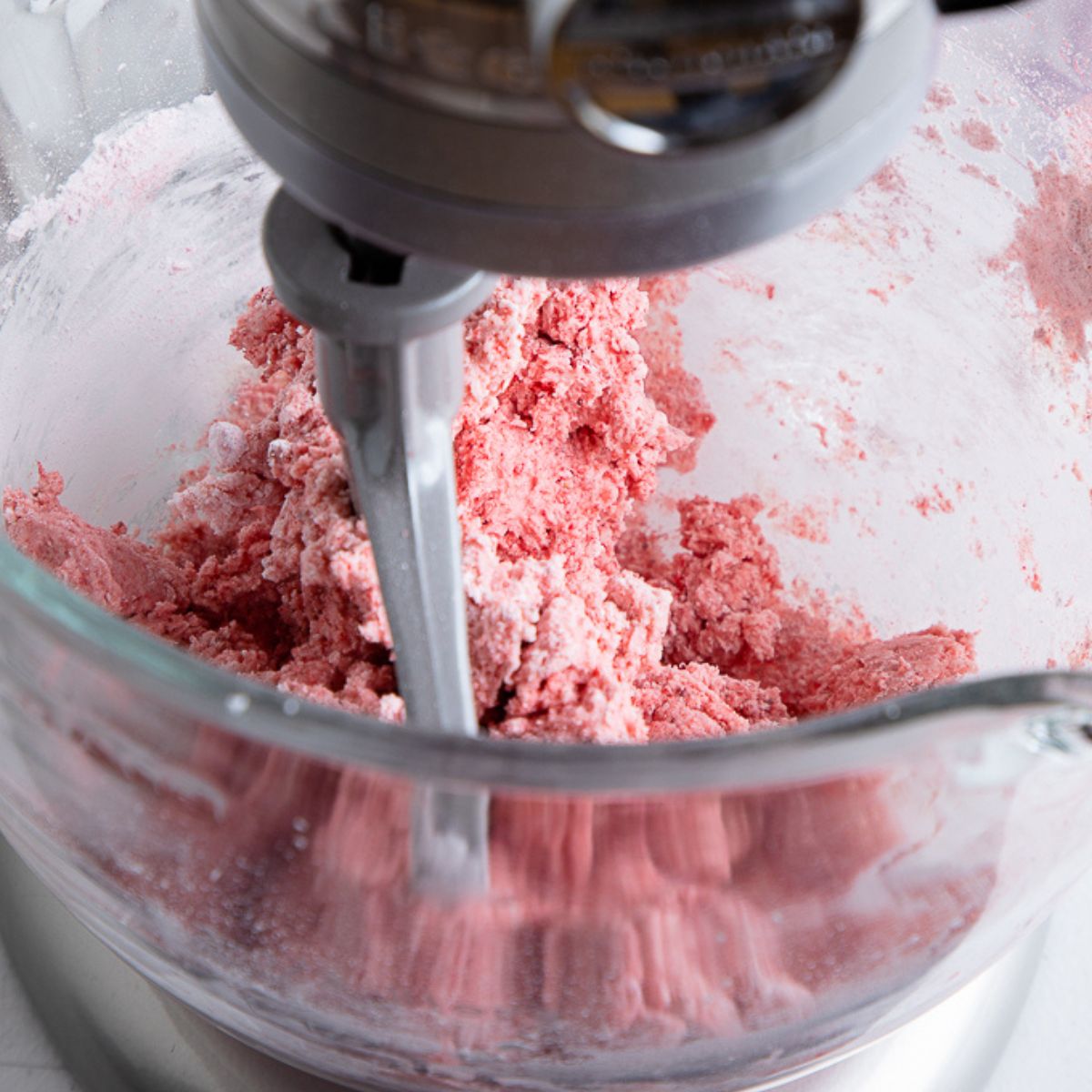 crumbly strawberry frosting in a grey standing mixer.