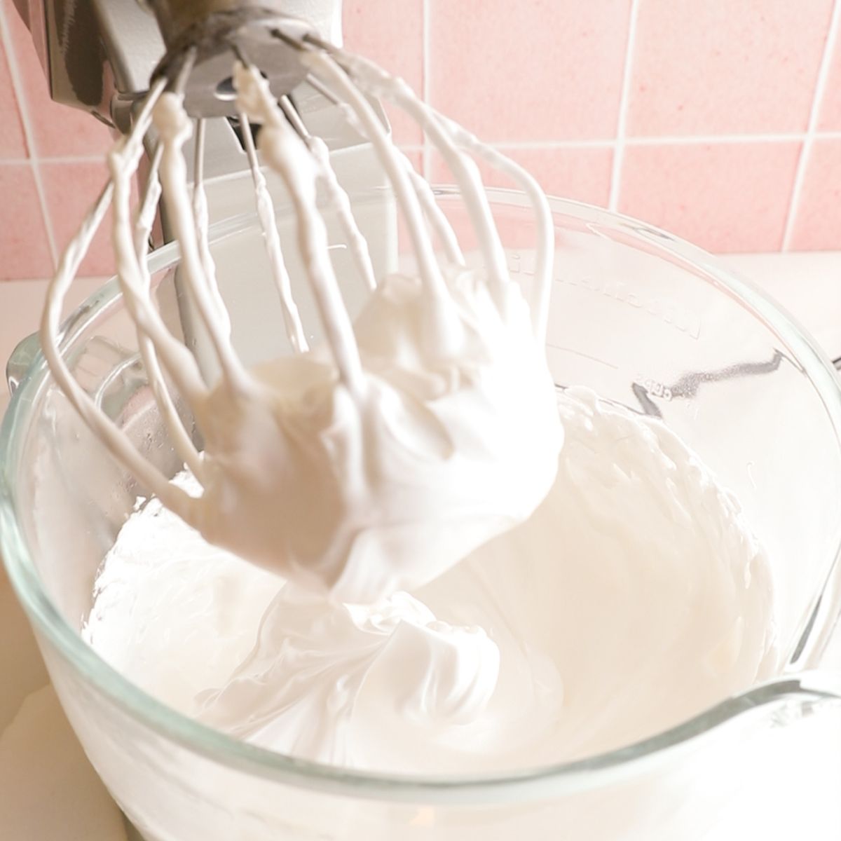 egg whites whipped with sugar syrup on a whisk attachment in a standing mixer.