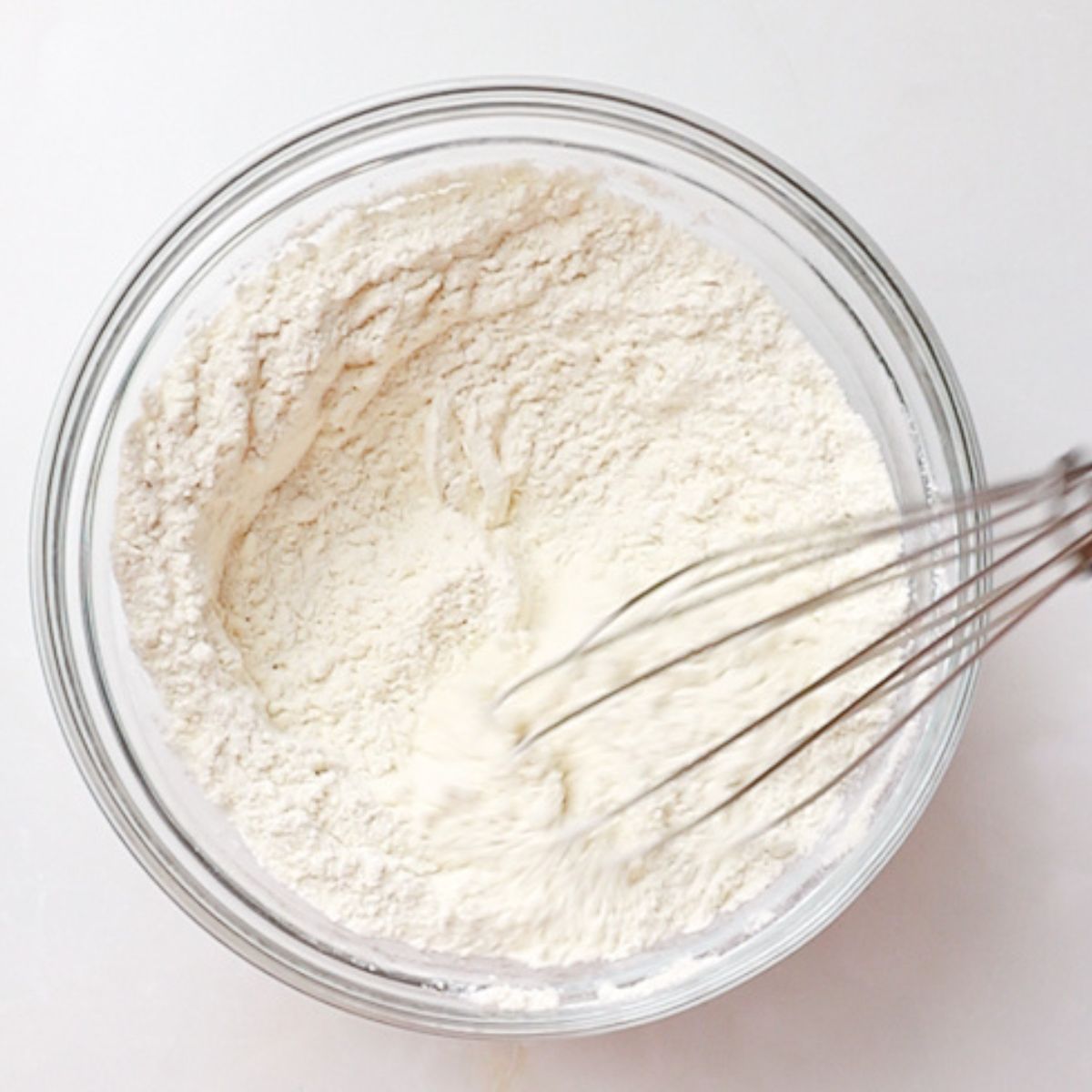 whisking flour, salt, and baking soda in a glass bowl.